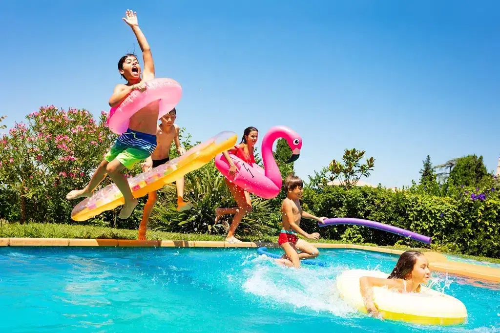 enfant qui sautent dans la piscine avec els bouées gonflables