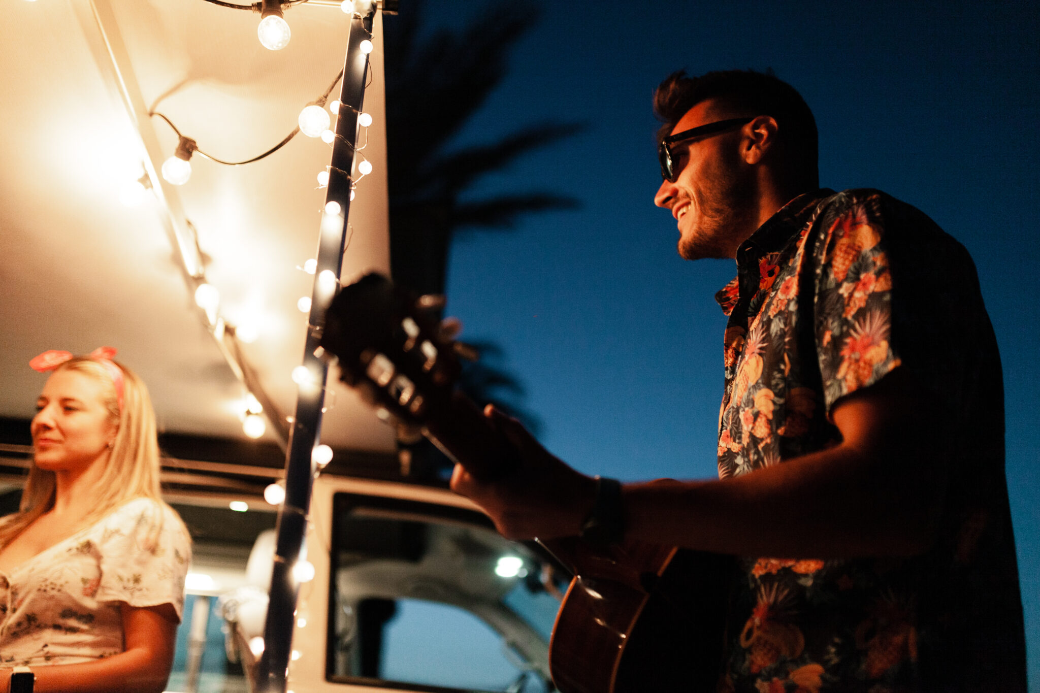 Party men are singing their friends at night near a camper van